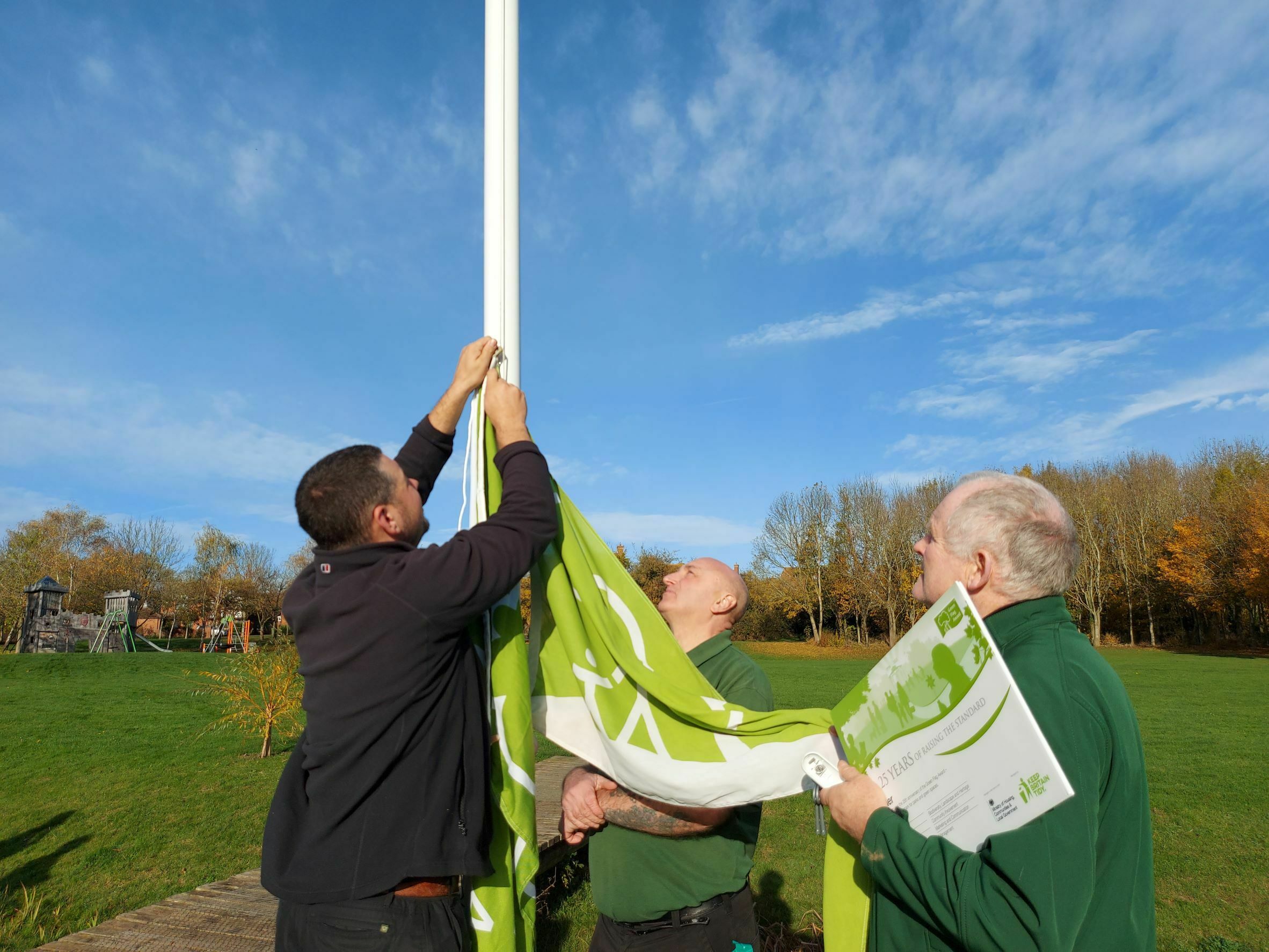 Three men begin to raise a green flag