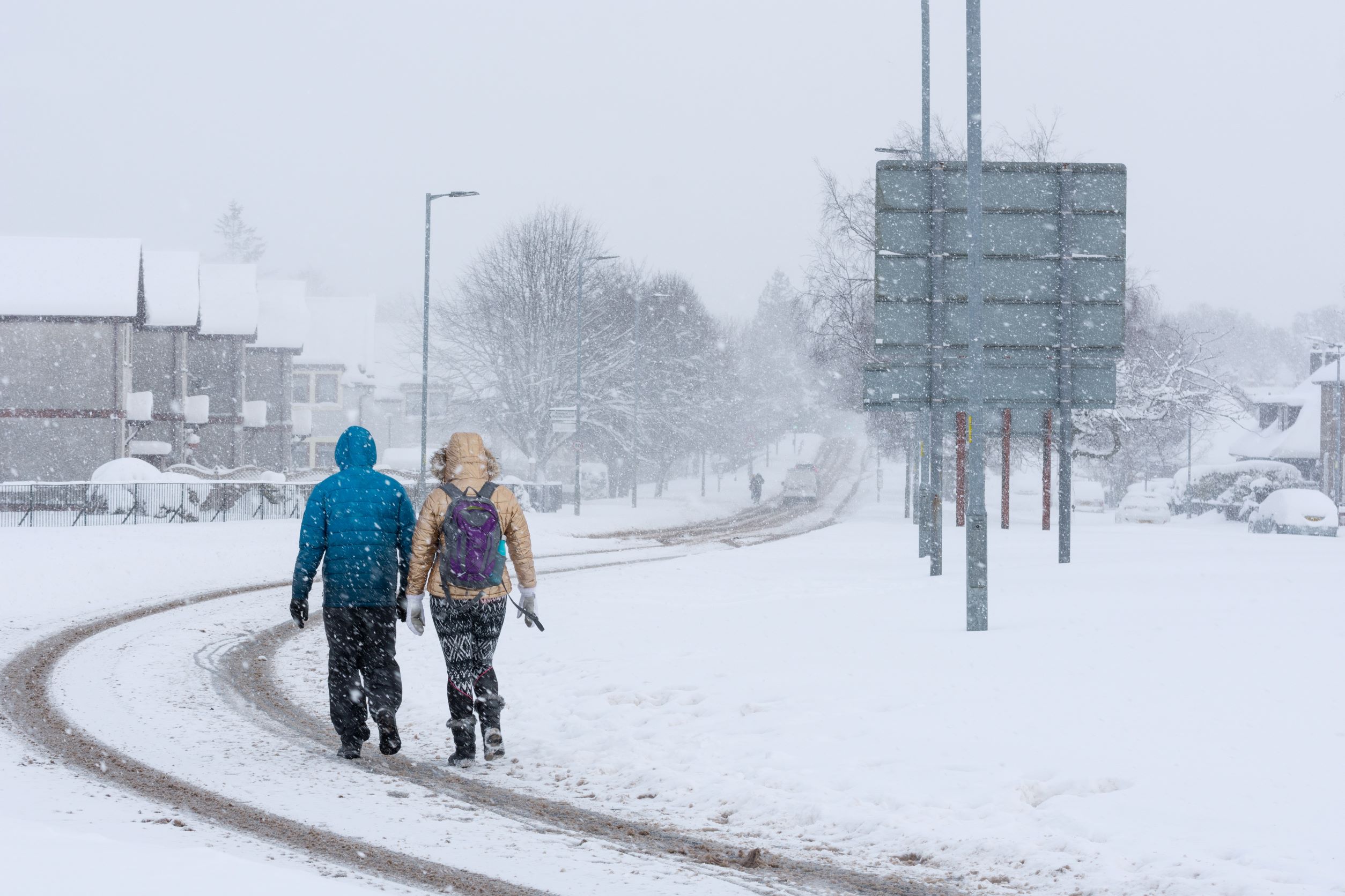 Two people walking along a snow-covered road