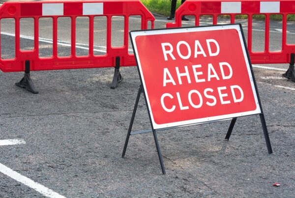 Road ahead closed sign with red barriers behind